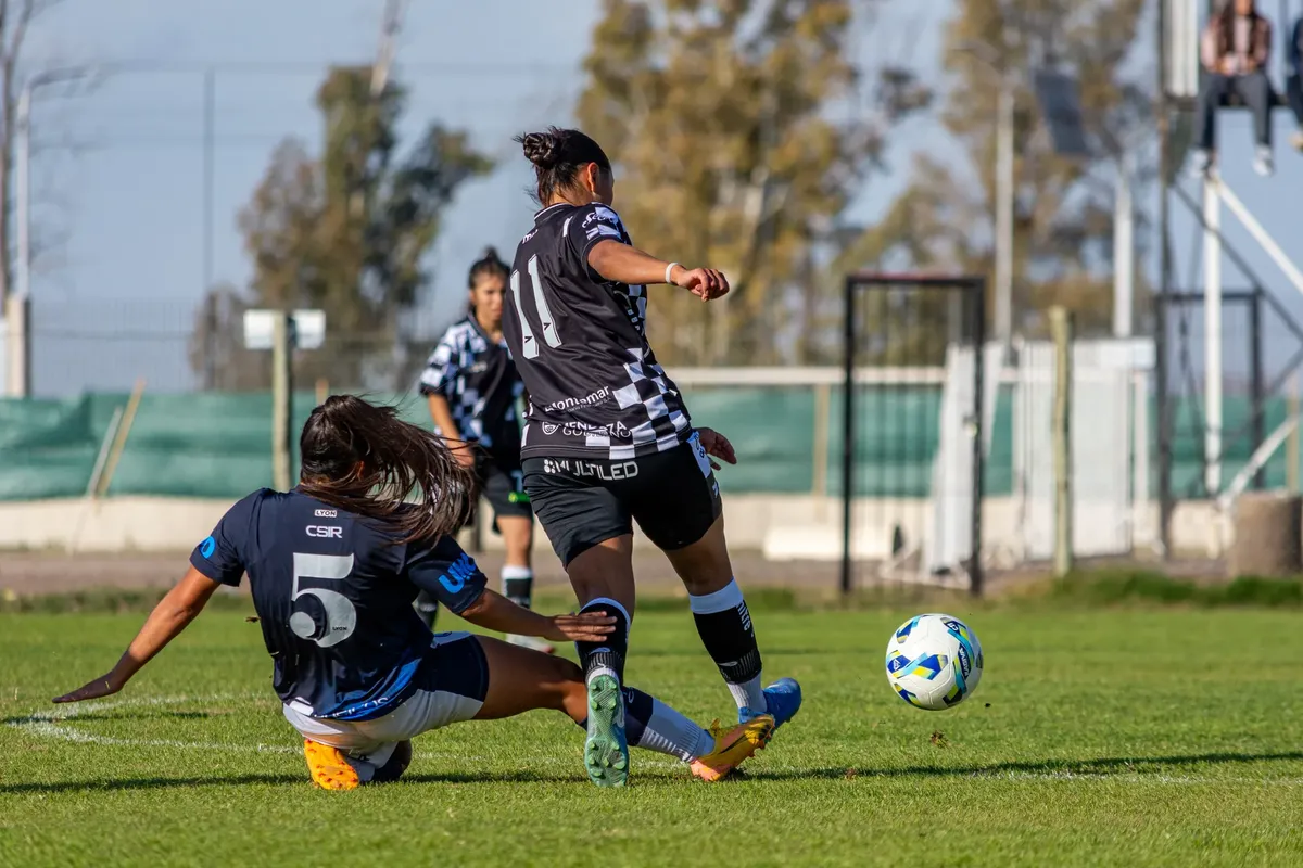 Two women soccer players in action during a competitive outdoor match.
