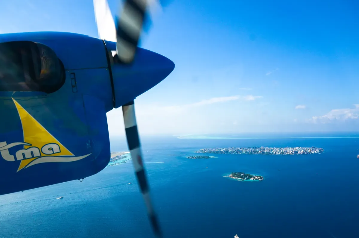 Seaplane flying over the Maldives showcasing clear blue water and lush islands.