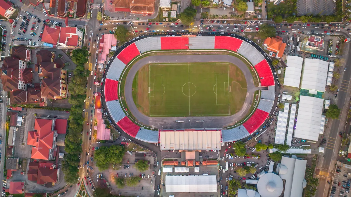 Drone shot of football stadium in Kota Bharu, surrounded by urban landscape.